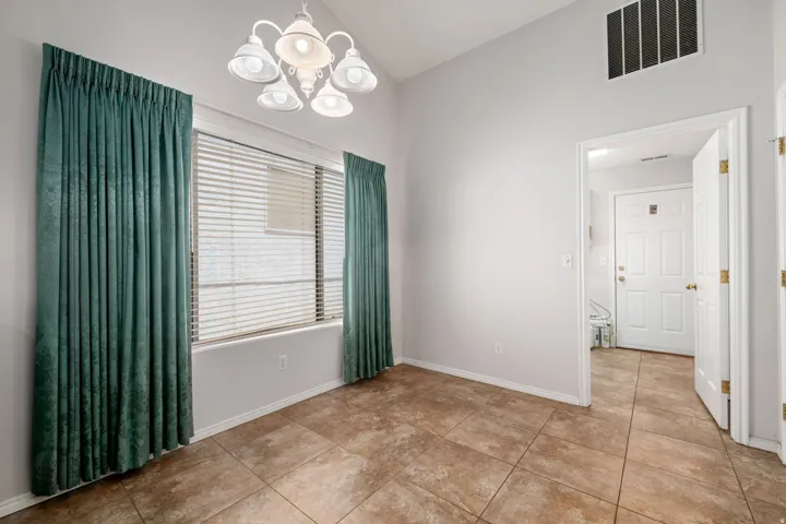 Spacious room featuring tile flooring, a large window with blinds and drapery, a ceiling-mounted light fixture, and light-toned wall paint