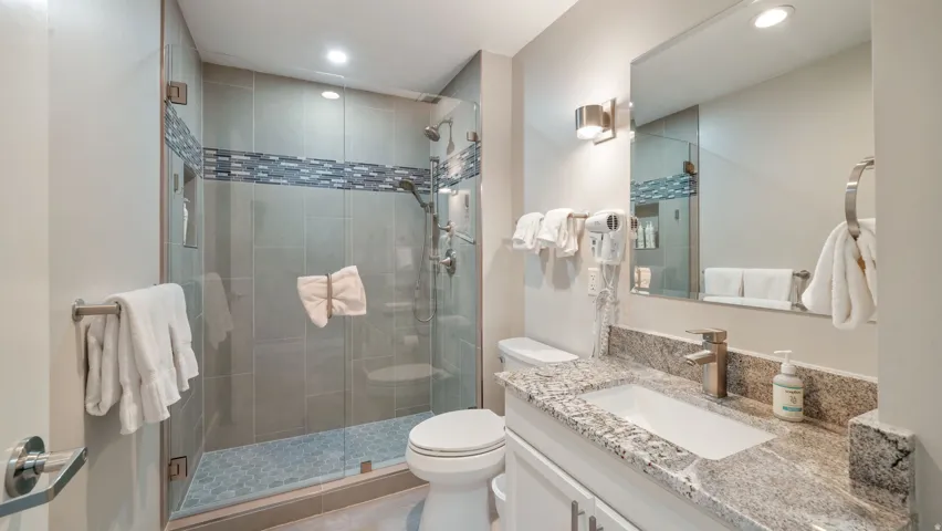 Bathroom featuring a glass-enclosed shower with tile surround and mosaic accent band