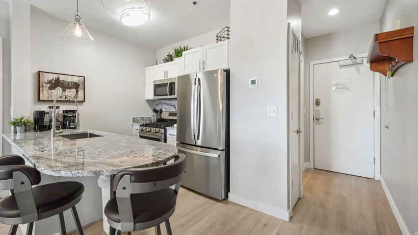 Modern kitchen featuring a granite-finish island with integrated sink and pendant lighting