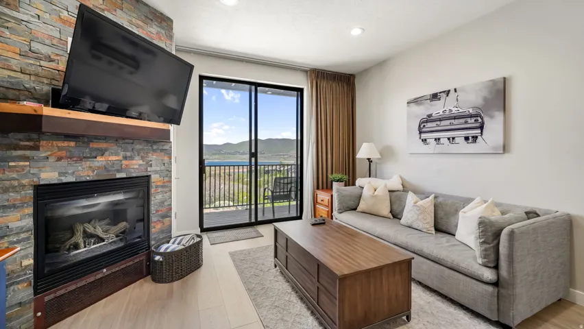 Living area featuring a floor-to-ceiling stone-faced fireplace with a wood mantel