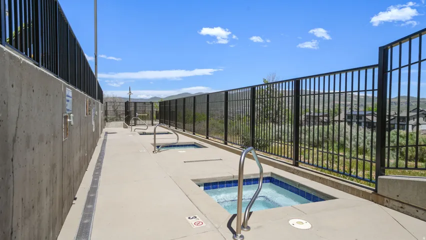 Outdoor amenity area featuring multiple hot tubs with blue tile interiors, concrete decking, and metal railings