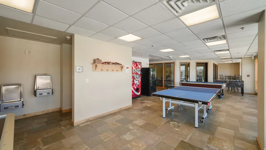 Recreation room featuring stone tile flooring, a suspended ceiling with recessed lighting, and a table tennis setup
