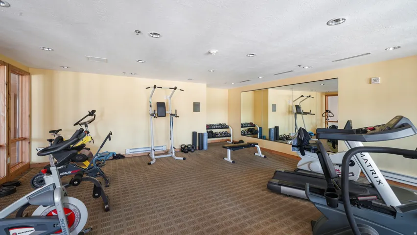Dedicated fitness area featuring patterned carpet flooring, recessed lighting, and a full-wall mirror