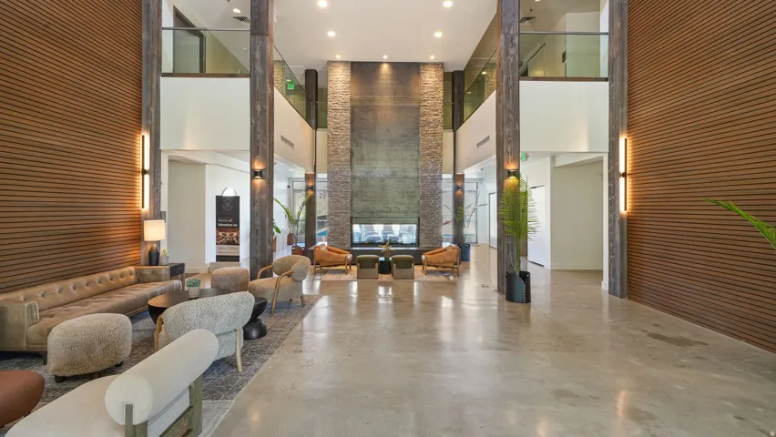 Open-concept communal lounge with high ceilings, concrete flooring, and a large fireplace feature wall