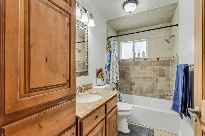 Bathroom with wood-finish cabinetry, a built-in sink with a light-toned countertop, and a vanity mirror