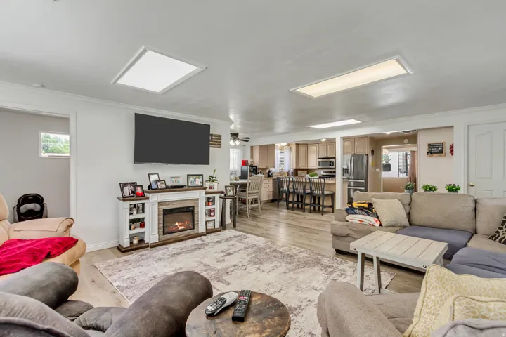 Open-concept living area featuring wood-finish flooring, recessed lighting, and a white decorative fireplace with an electric insert