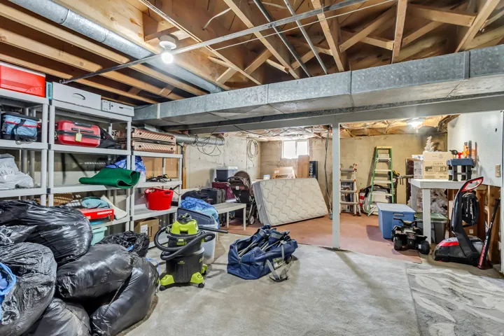 Unfinished basement offering exposed ceiling joists and concrete flooring