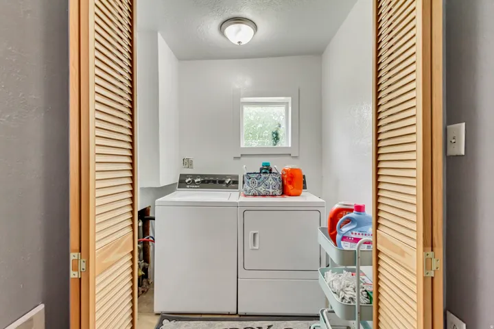 Laundry area featuring louvered bi-fold doors, a window, and overhead lighting