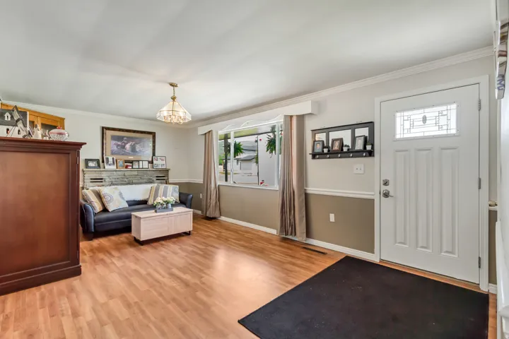 Entryway and living area featuring wood-finish flooring, a decorative front door with an ornate glass insert, and a stone-clad fireplace