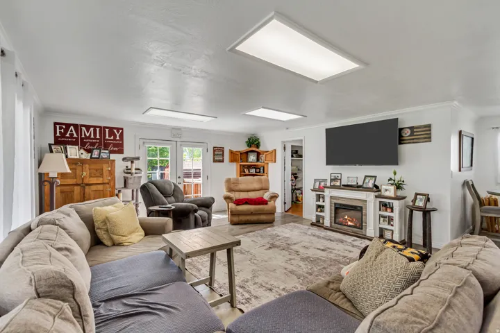 Spacious living area featuring light wood-finish flooring, a built-in fireplace with display shelving, and white French doors