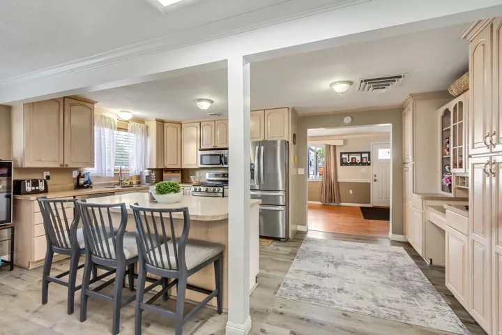 Kitchen featuring light-tone cabinetry, stainless steel appliances, a breakfast bar with seating, light-finish countertops, and wood-finish flooring