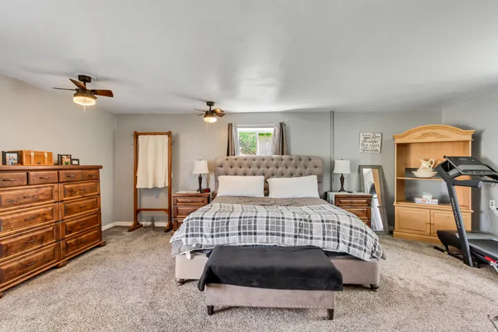 Spacious room featuring neutral wall tones, textured carpeting, and two ceiling fans with integrated lighting