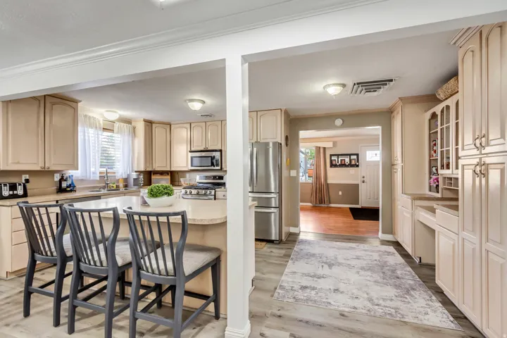 Kitchen featuring an island with seating, stainless steel appliances, ample cabinetry, wood-finish flooring, and a window above the sink