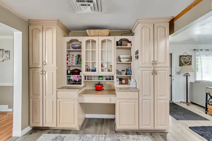 Built-in cabinetry with glass-front display cabinets, integrated desk space, and light-toned countertops
