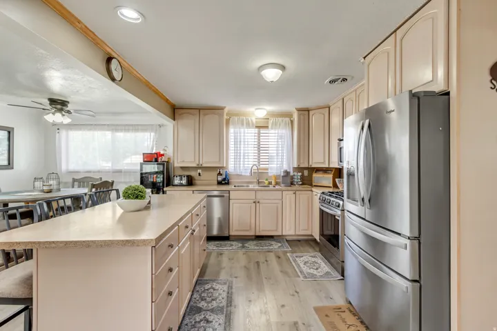 Kitchen featuring light wood-finish cabinetry, a central island with countertop seating, stainless steel appliances, and wood-finish flooring