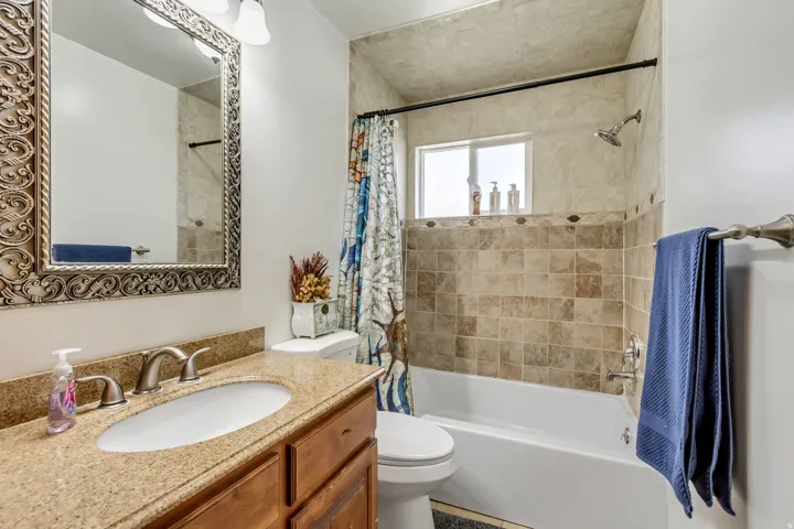Bathroom featuring a vanity with a granite-style countertop, an undermount sink, and a framed mirror