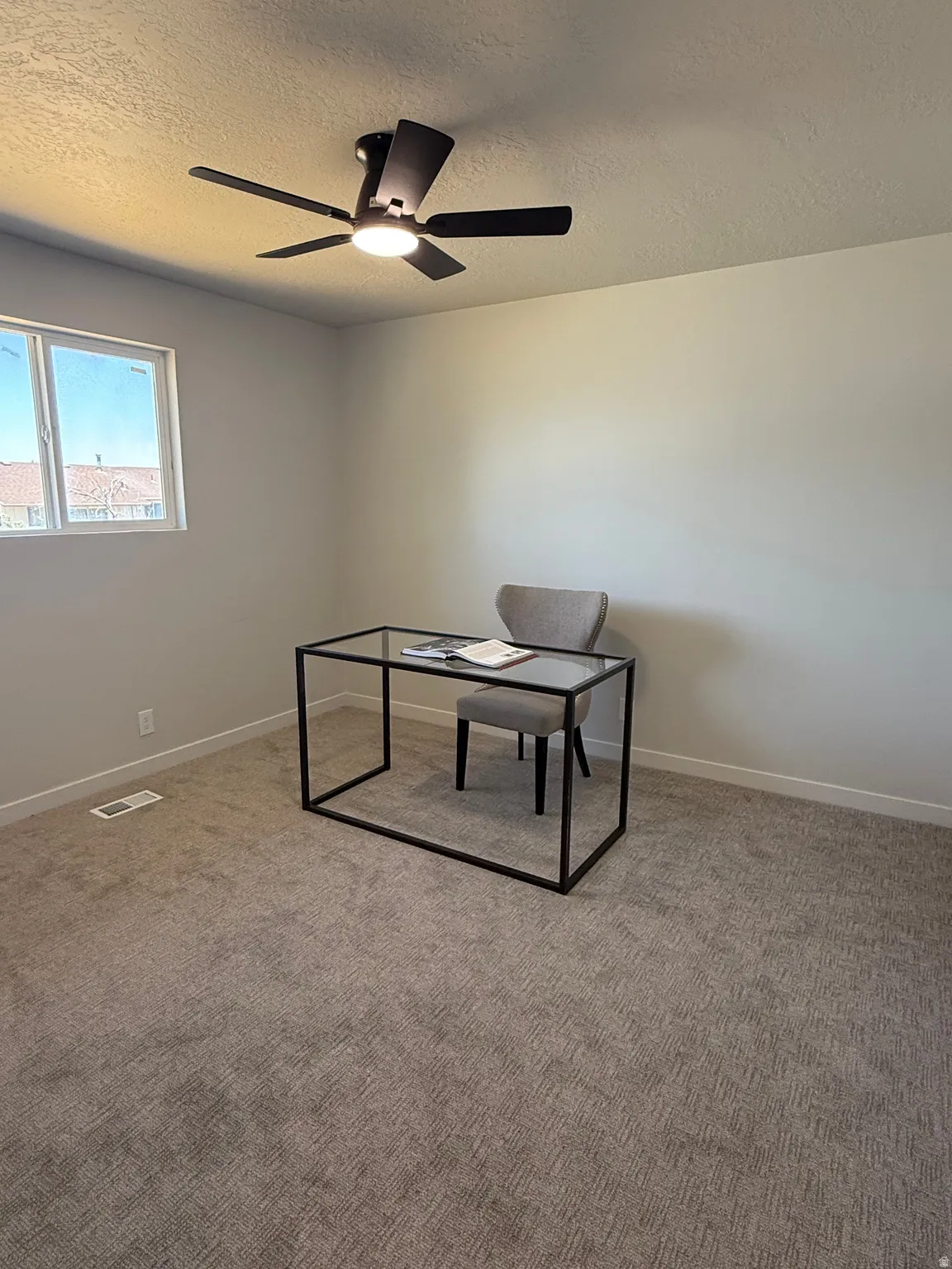 Light-filled room featuring neutral wall tones and textured carpeting