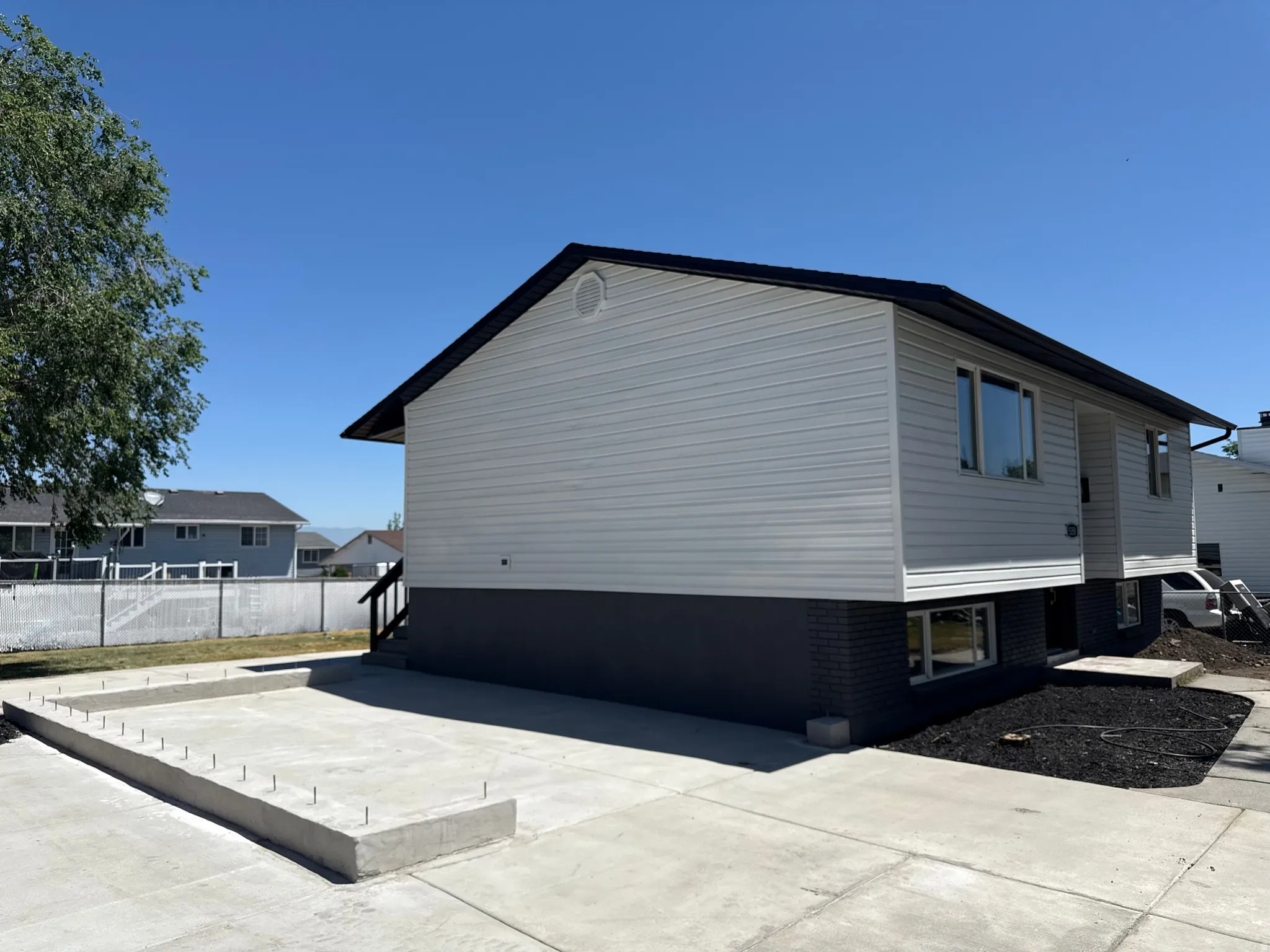 Exterior featuring light gray siding, dark gray brick foundation, and a contrasting dark roofline