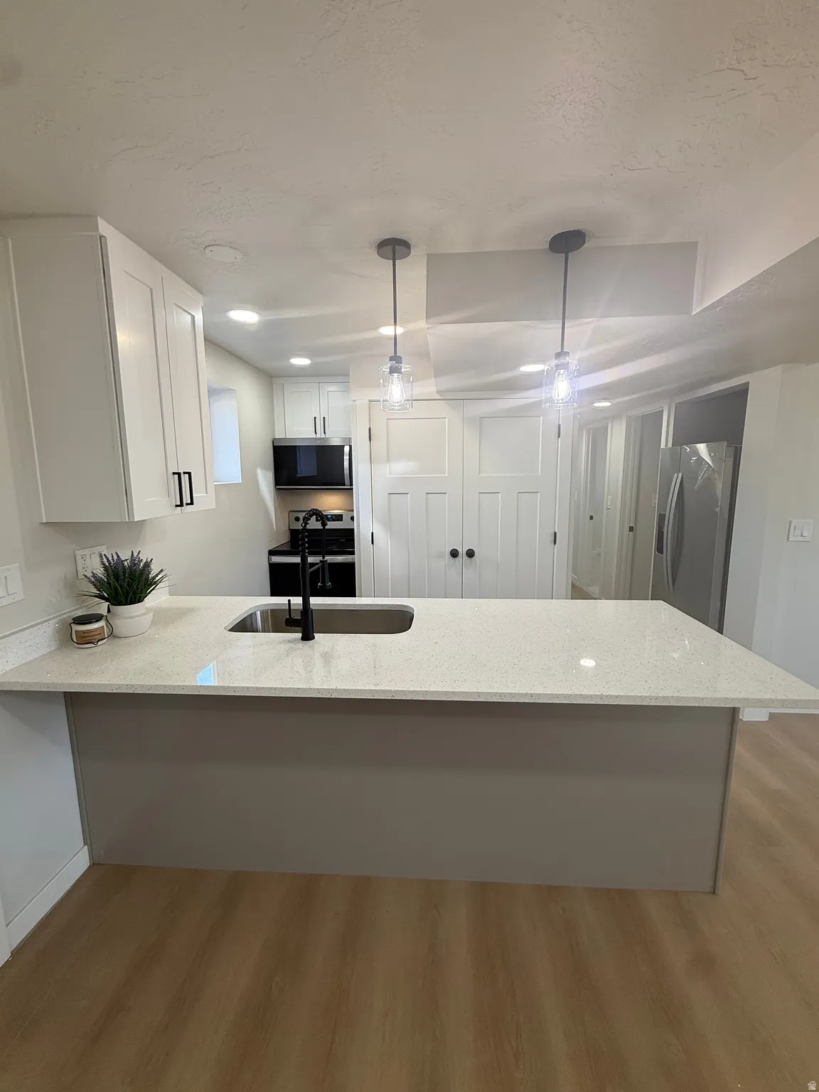 Kitchen island with light-toned countertop and integrated sink