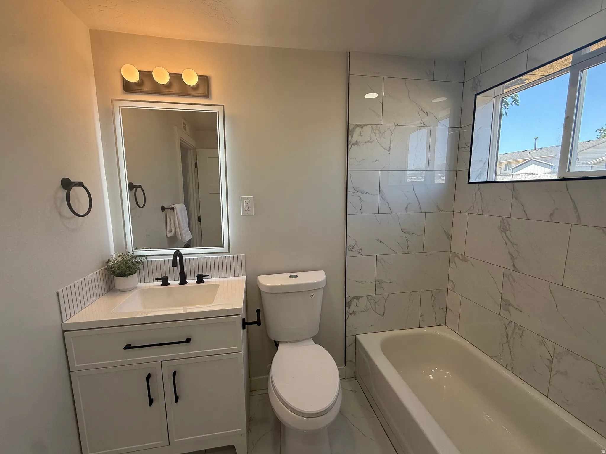 Bathroom featuring a white vanity with black hardware, a matte black faucet, and a rectangular mirror