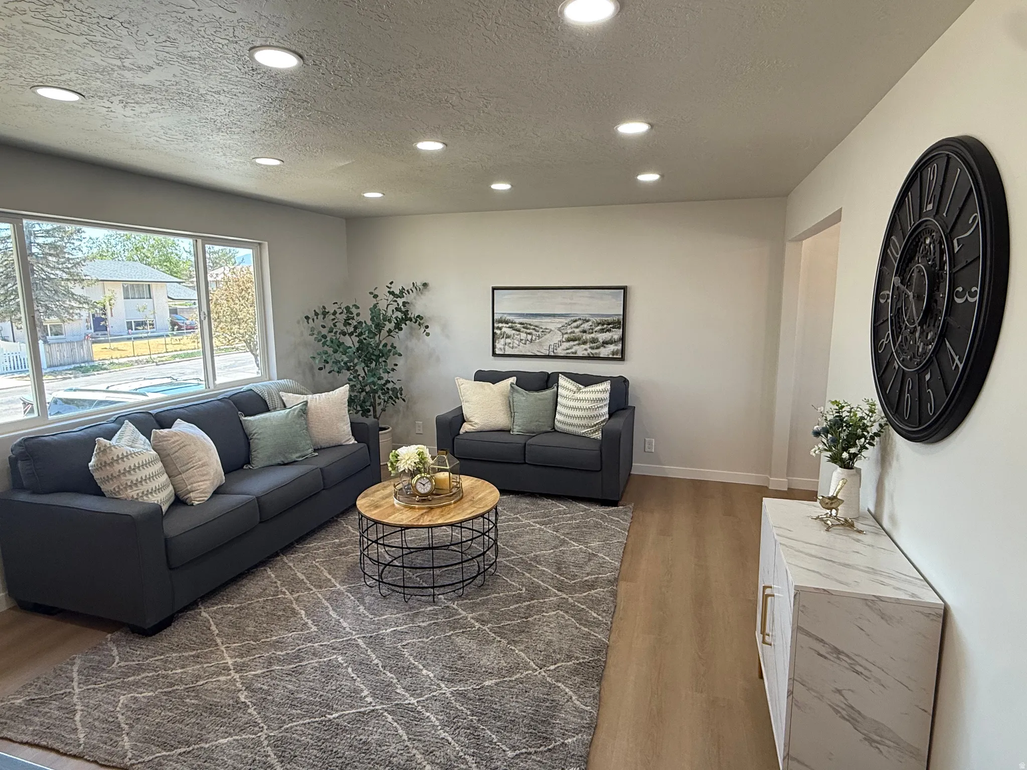 Spacious living area featuring expansive windows, recessed lighting, wood-finish flooring, and light-toned wall finishes