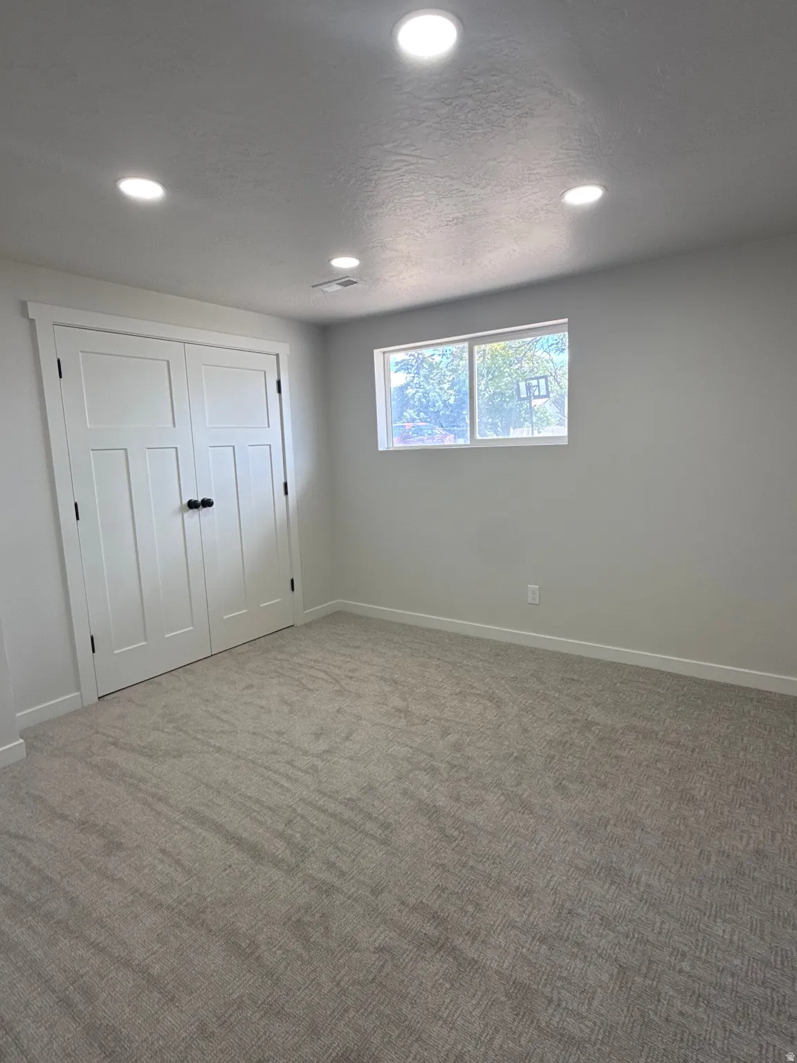 Neutral wall tones complemented by recessed lighting and a window with exterior views