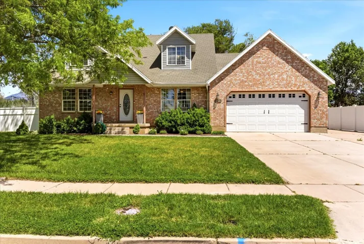 Brick and siding exterior featuring a covered porch entry, a two-car garage, and a dormer window