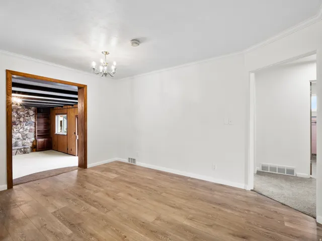 Wood-finish flooring throughout the main area with white painted walls and crown molding