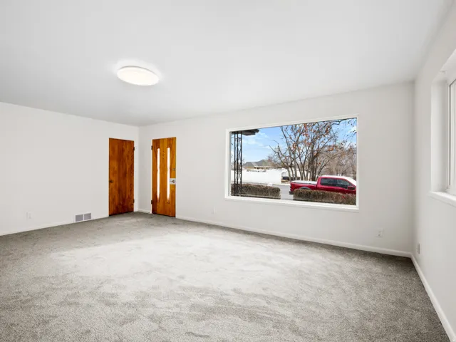 Spacious interior featuring neutral wall paint, light gray carpeting, and a large front window