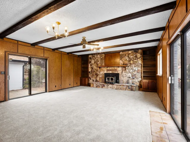 Spacious living area featuring a stone-clad fireplace with a wood-burning insert and mantel