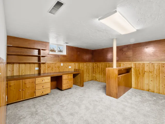 Wood-paneled room featuring built-in cabinetry, shelving, and a desk workstation