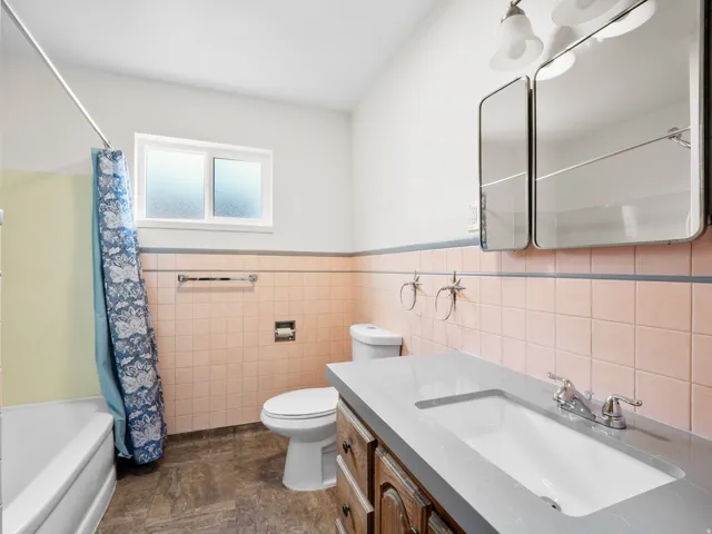 Bathroom featuring a white bathtub, pink wall tiling with a gray accent line, and a white framed window