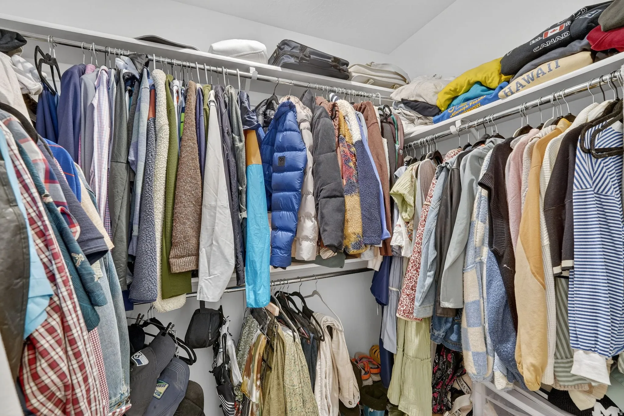 Walk-in closet featuring white wire shelving, multiple hanging rods, and ample storage space