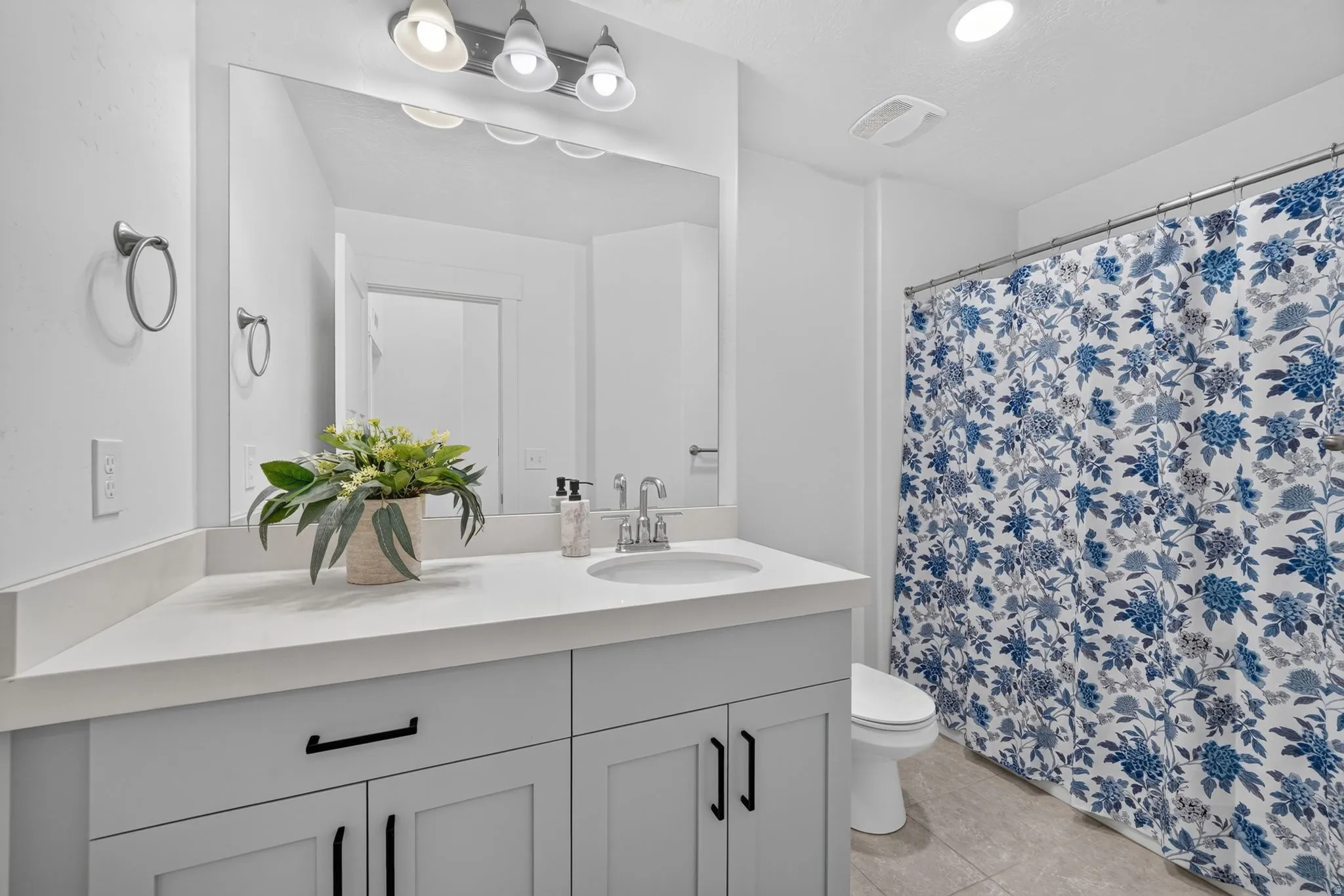 Bathroom featuring a single vanity with light cabinetry, a white countertop, and an undermount sink