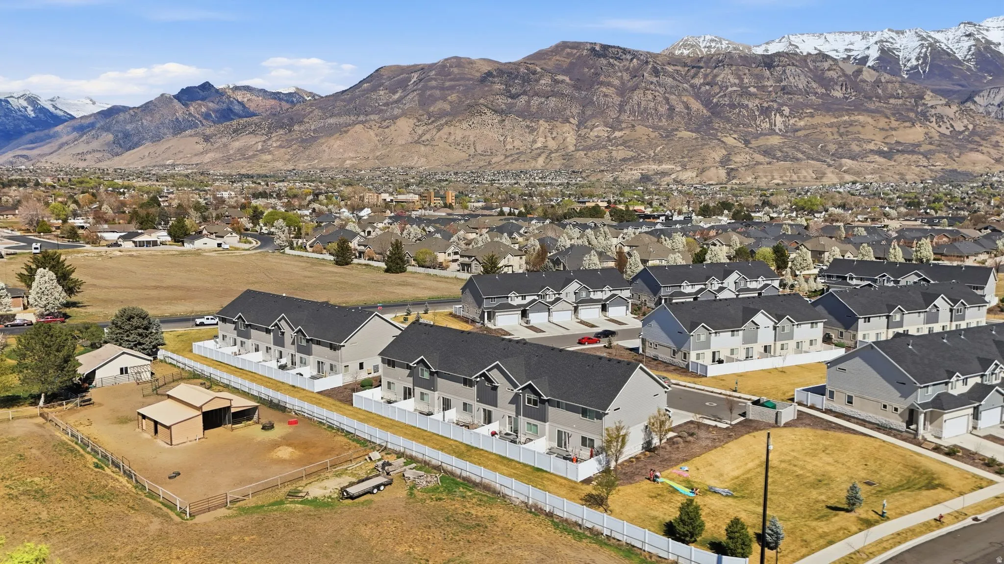 Newly constructed townhomes featuring contemporary exterior finishes, private patios, and white perimeter fencing