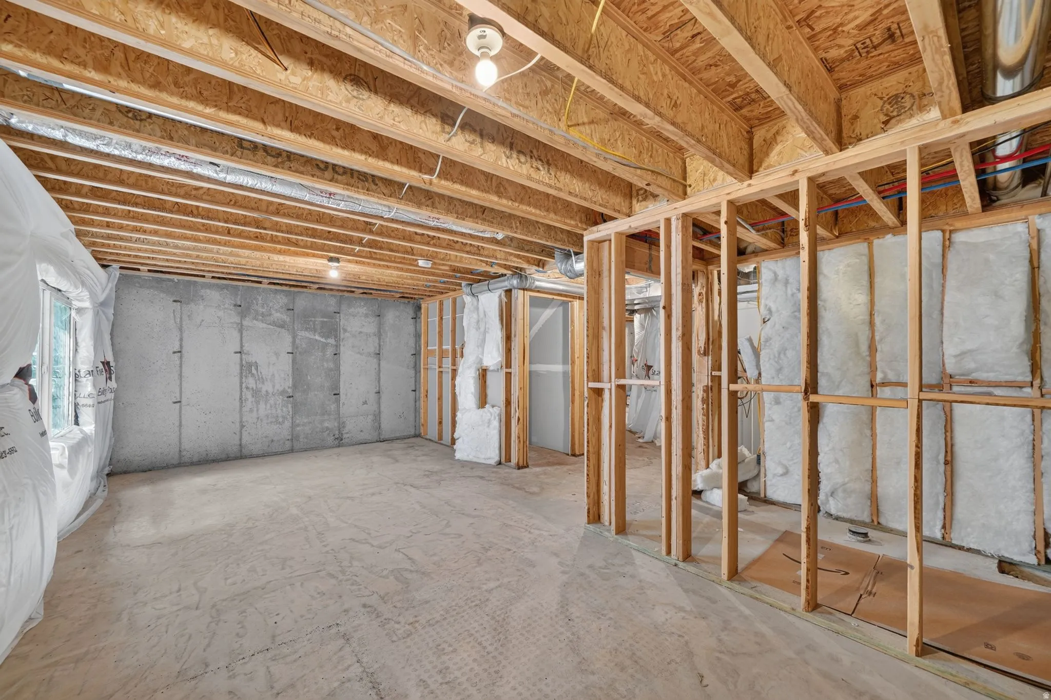 Unfinished basement offering exposed wood joists, concrete foundation walls, and framed interior partitions with visible insulation