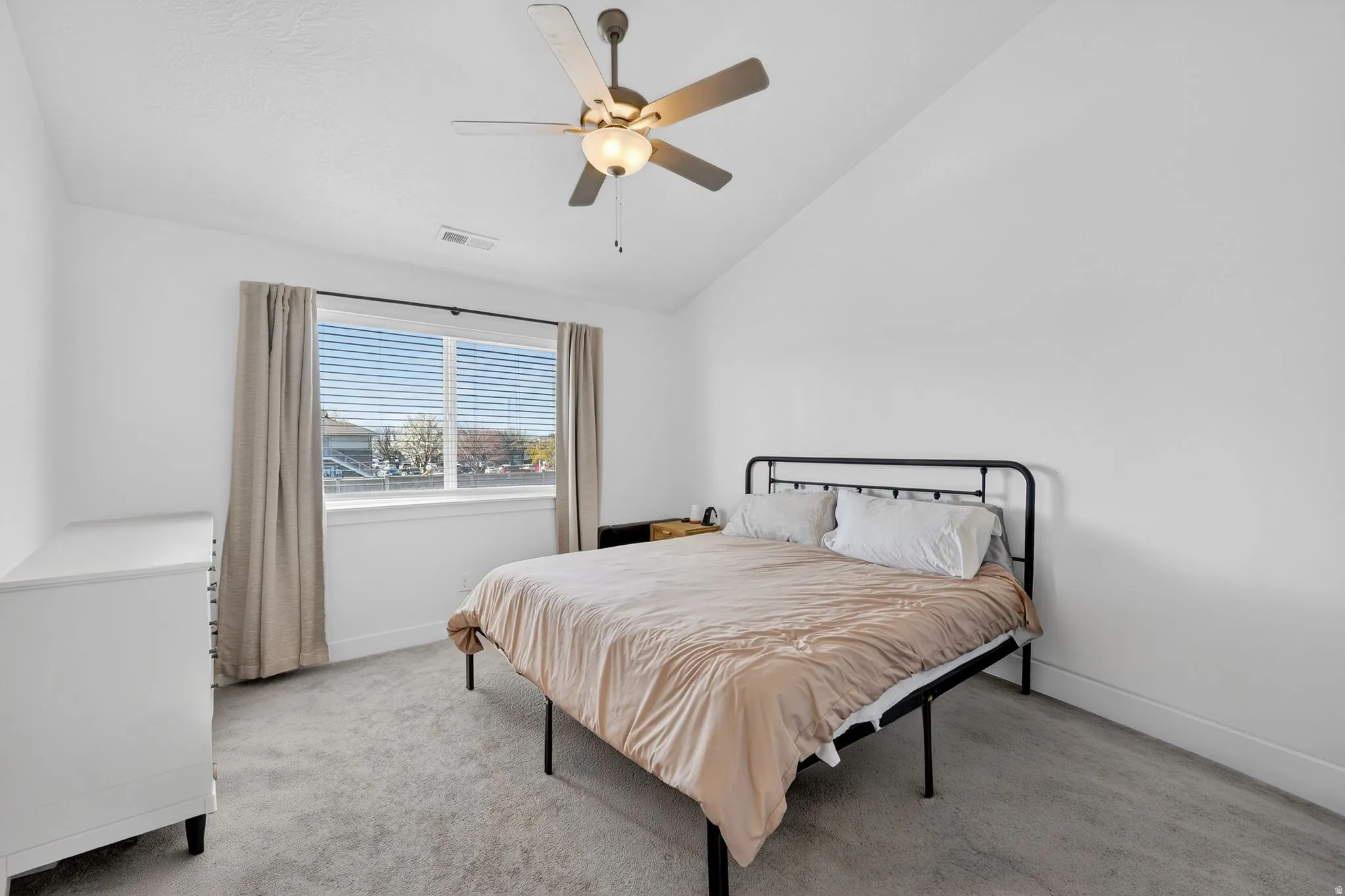 Bright room with a vaulted ceiling, ceiling fan, and window featuring horizontal blinds