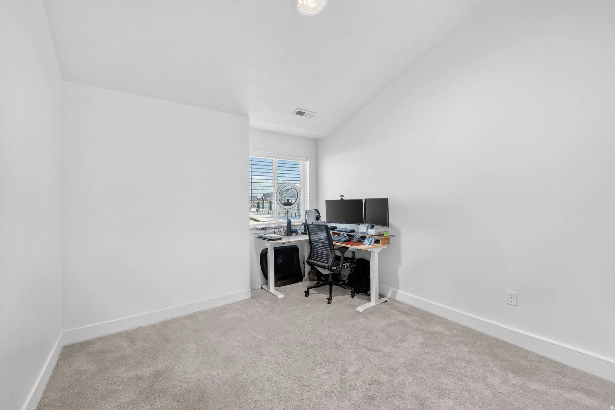 Carpeted room featuring a single window with horizontal blinds, a vaulted ceiling, and white baseboards