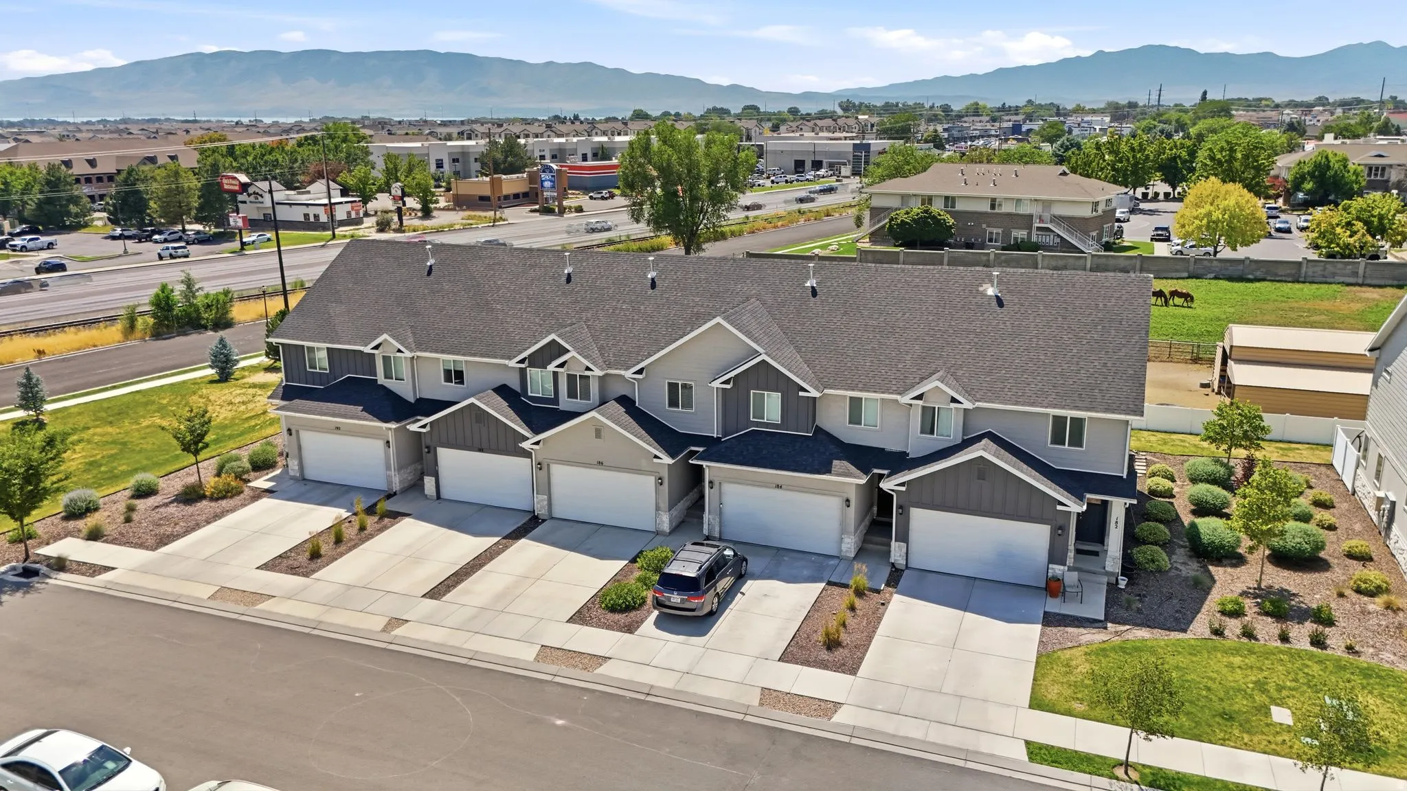 Contemporary townhome-style residences featuring two-story facades, attached garages, and individual concrete driveways