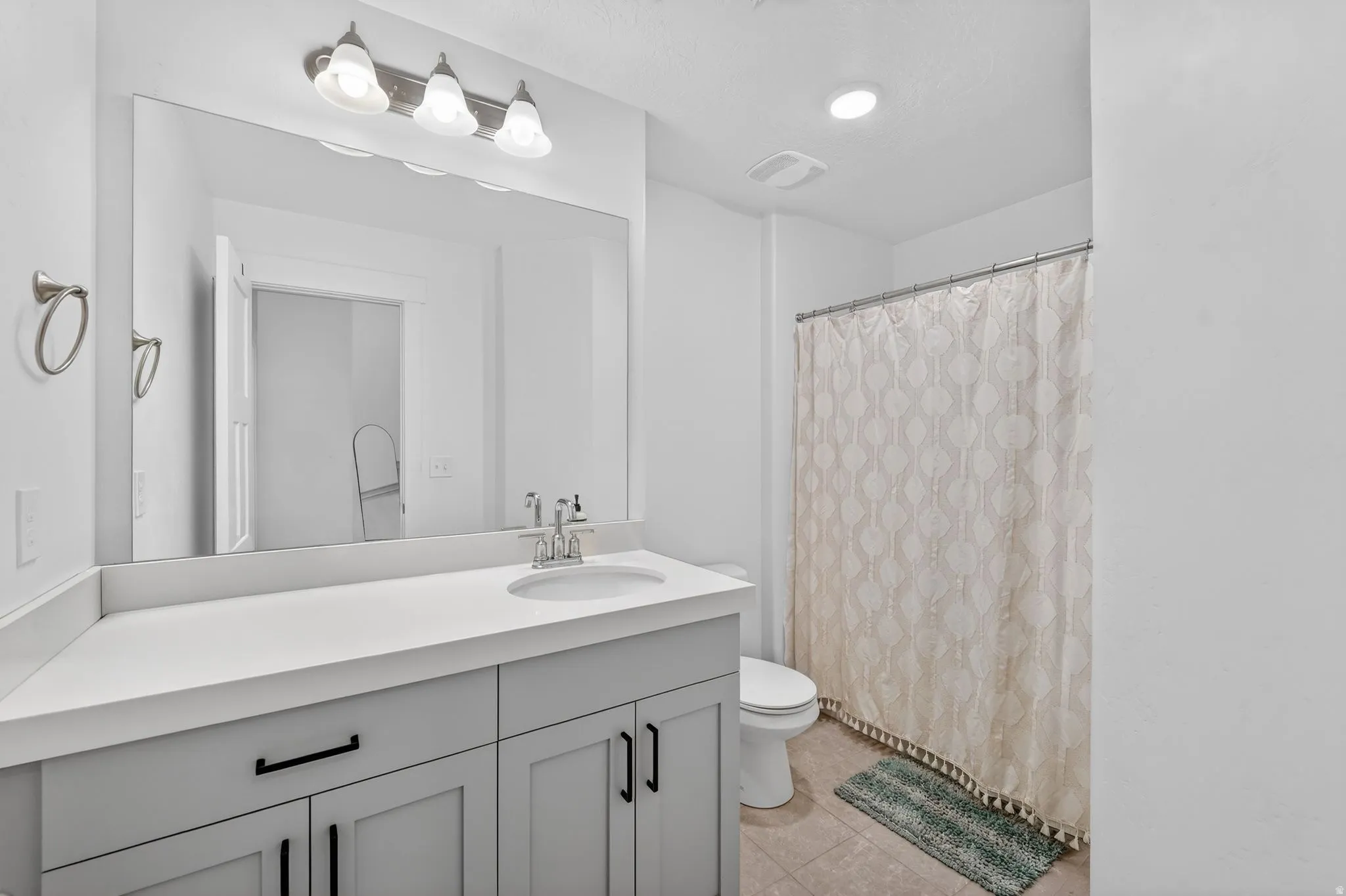 Bathroom featuring a single vanity with light grey cabinetry and a white countertop