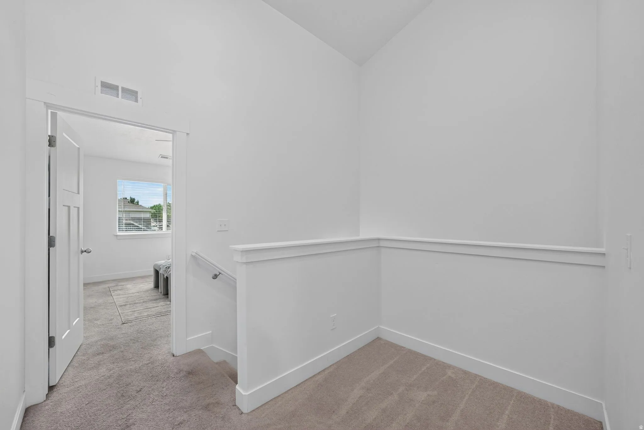 Upper-level landing area featuring neutral carpeting, a staircase with a white railing, and a crisp white wall palette