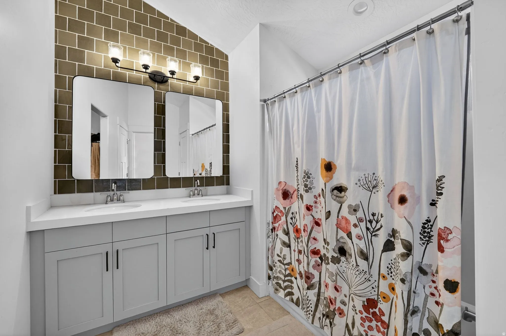 Dual vanity featuring a white countertop with integrated sinks, light gray cabinetry, and matte black hardware