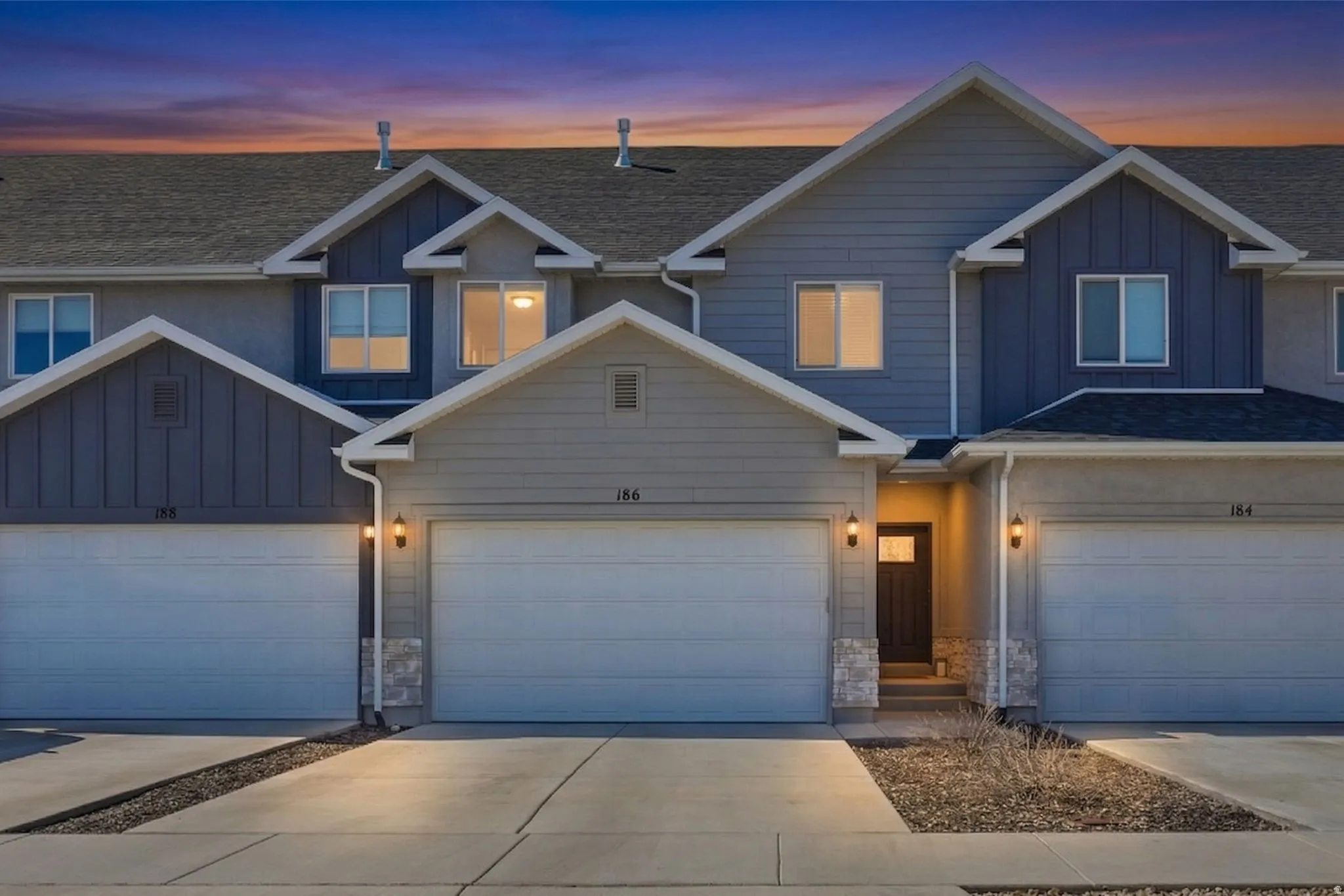 Contemporary townhome exterior featuring multi-toned siding, gabled rooflines, and multiple windows