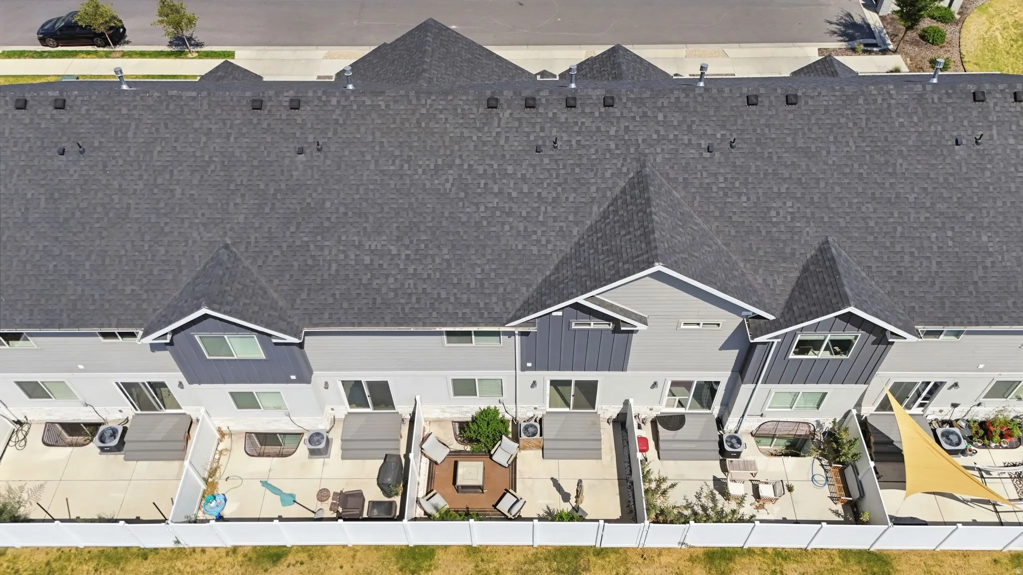 Row of contemporary townhomes featuring dark shingle roofs and light grey siding with dark grey accents