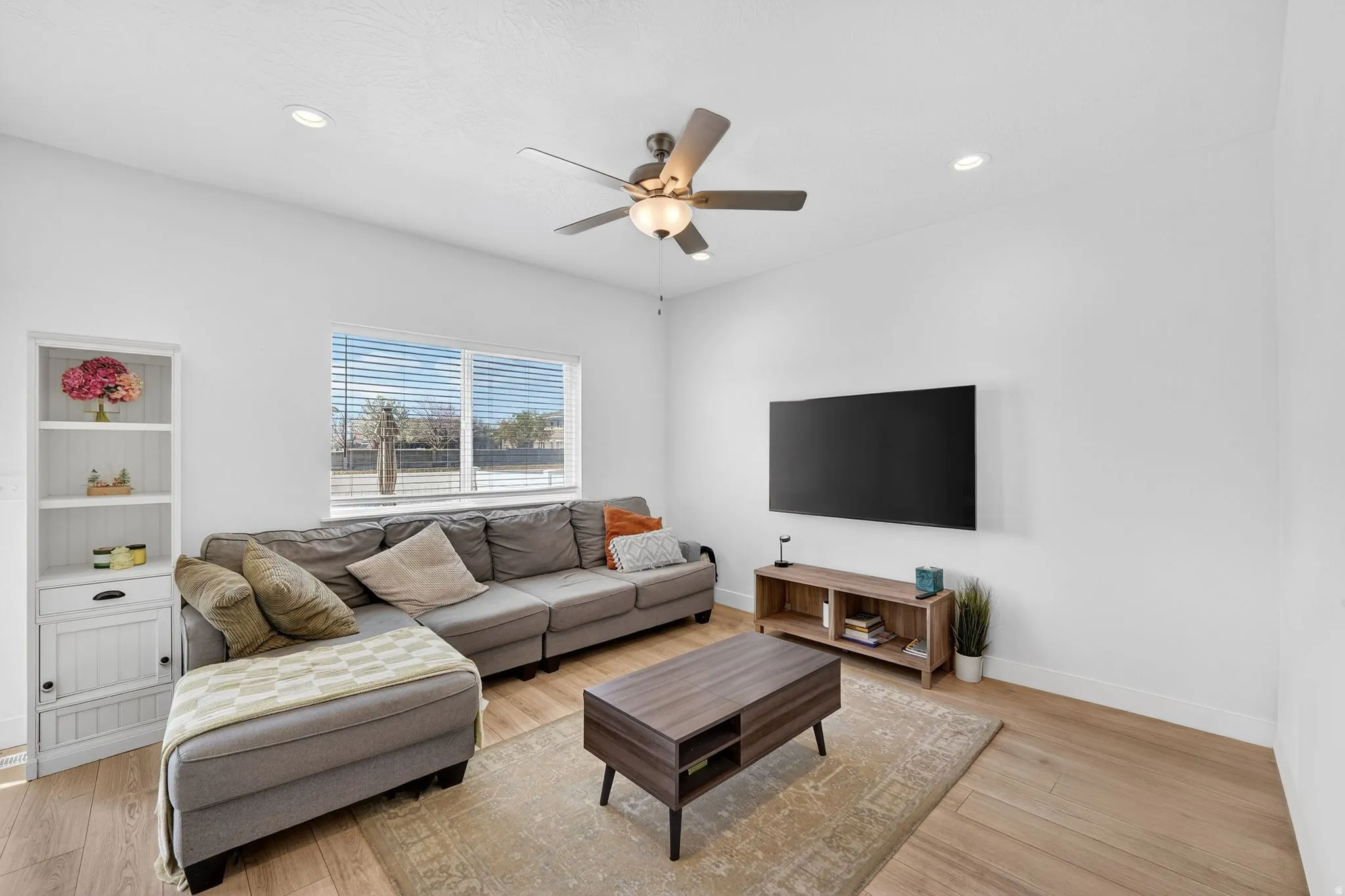 Bright living area featuring wood-finish flooring, recessed lighting, and a ceiling fan