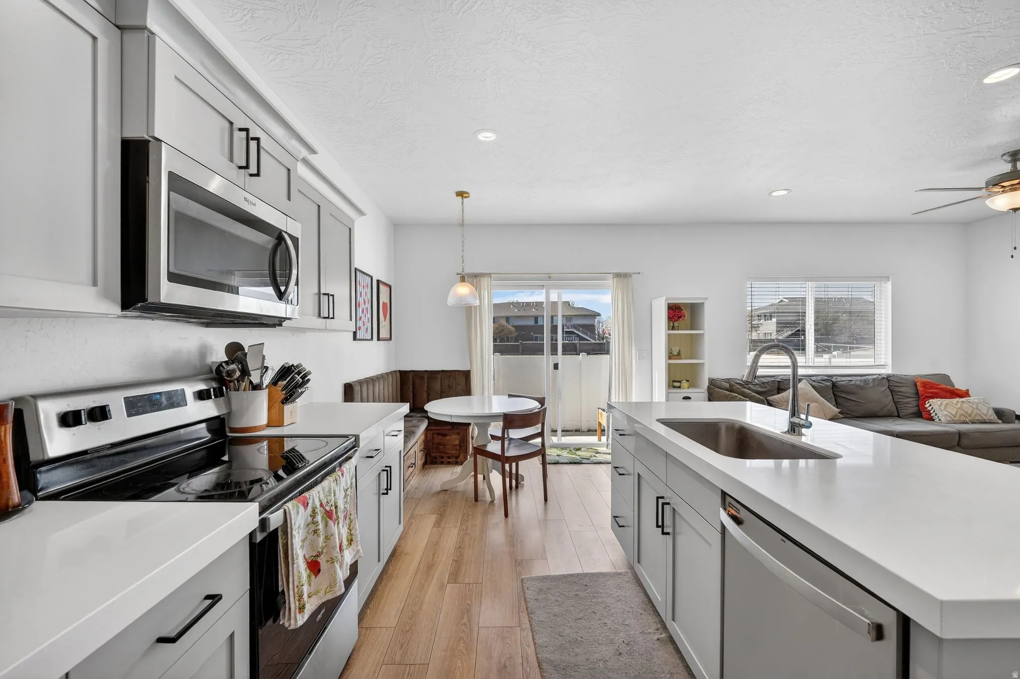 Modern kitchen featuring light wood-finish flooring, white countertops, and light gray cabinetry