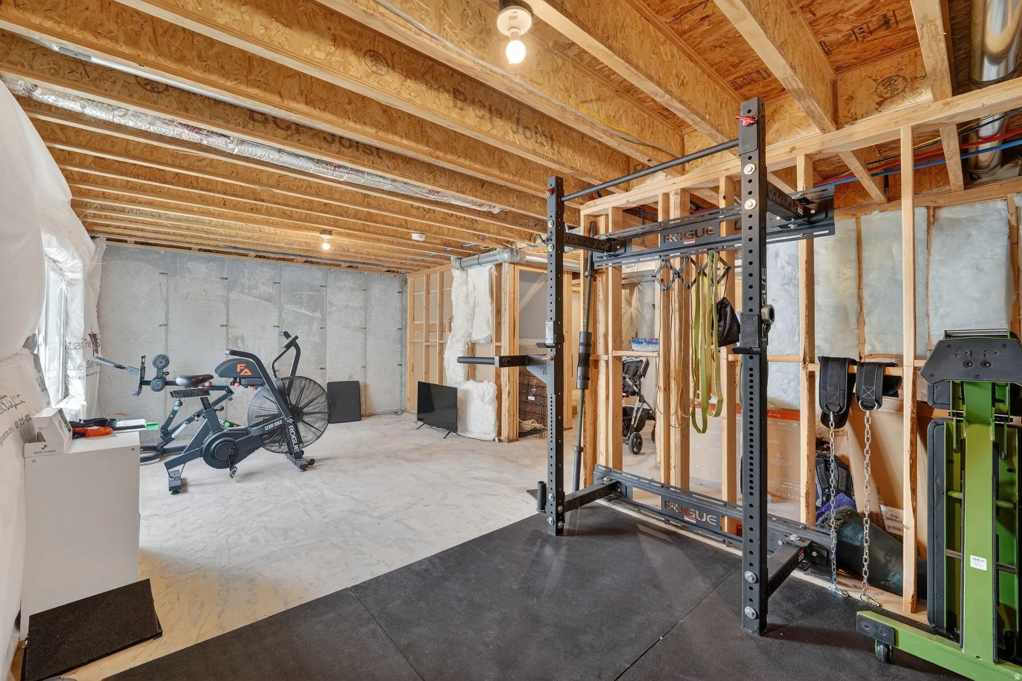 Unfinished basement featuring exposed wood joists, concrete walls, and framed sections