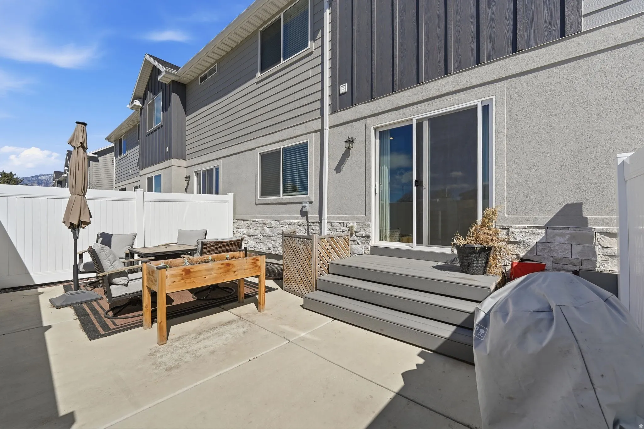 Private patio area featuring a concrete surface and white privacy fencing