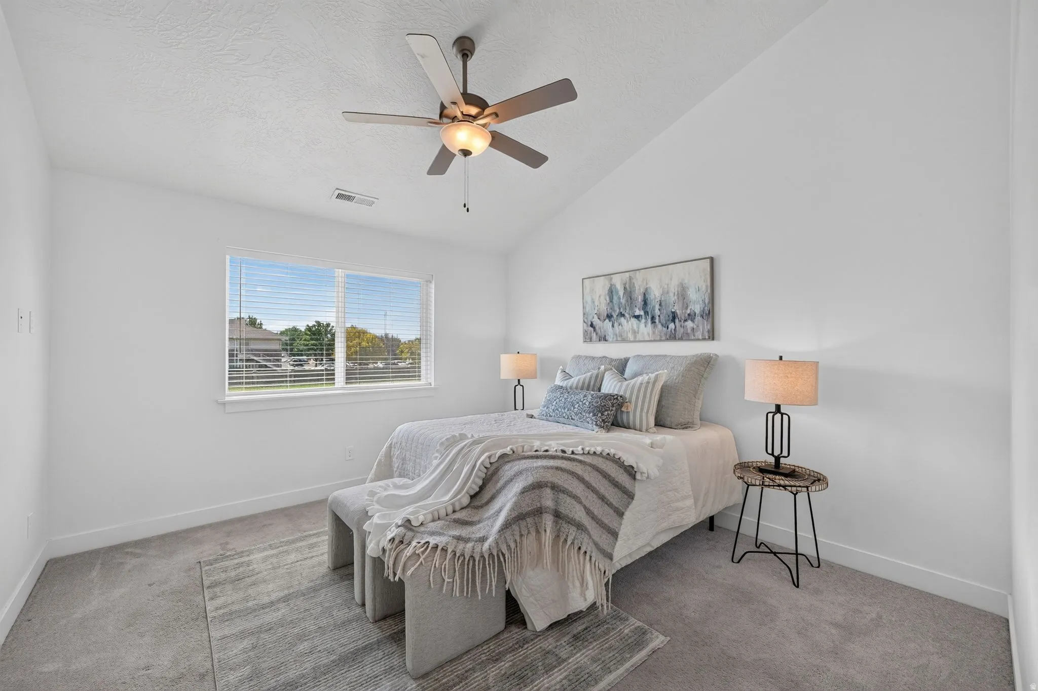 Spacious room featuring vaulted ceilings, a ceiling fan with integrated lighting, and a large window with blinds