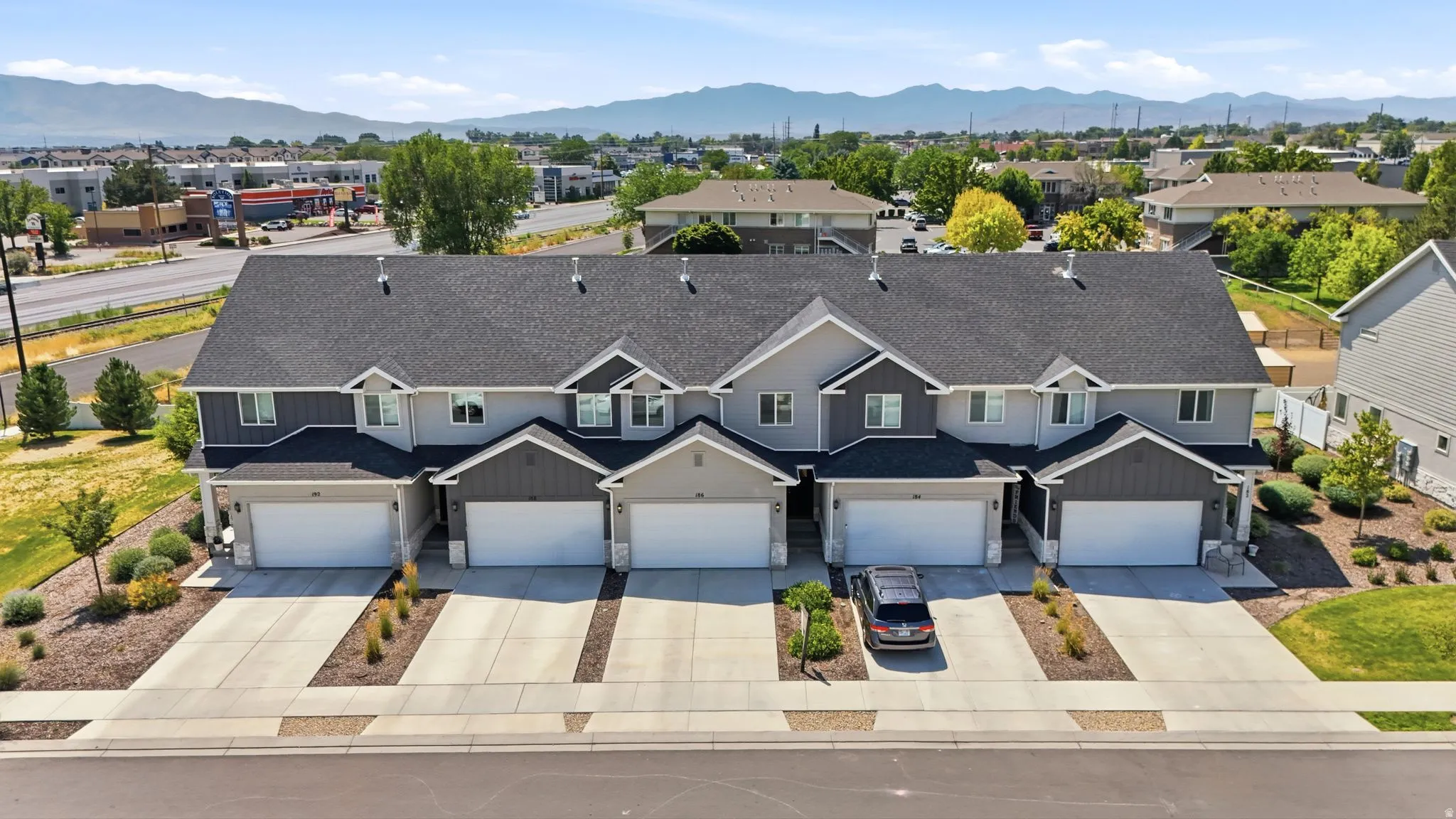 Contemporary multi-unit residence featuring a dark shingle roof and light grey siding